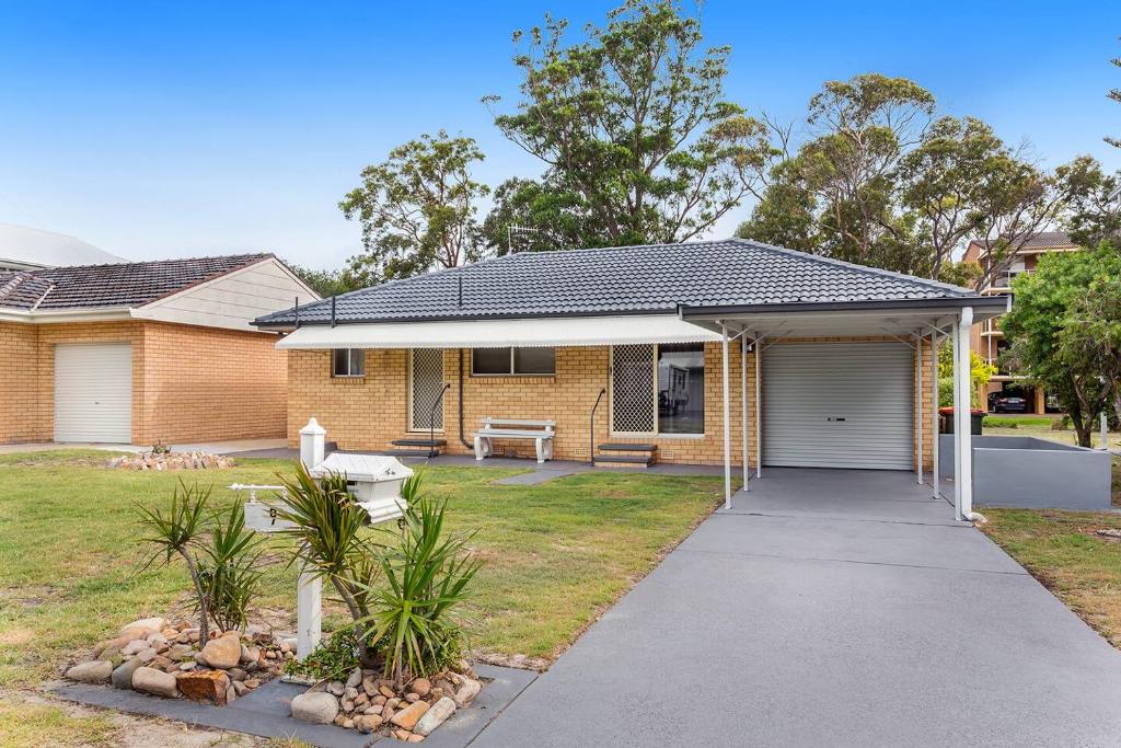 a brick house with a garage in a yard at Barefoot Bungalow in Nelson Bay