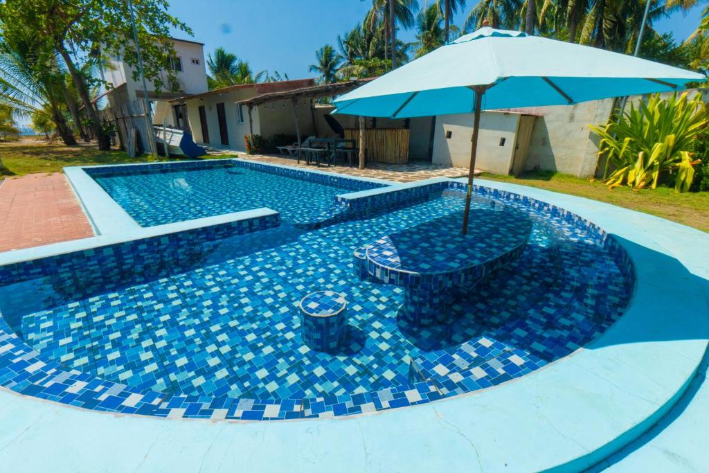 a swimming pool with an umbrella and a table and sidx sidx sidx sidx at Ocean Paradise in Barra de Santiago
