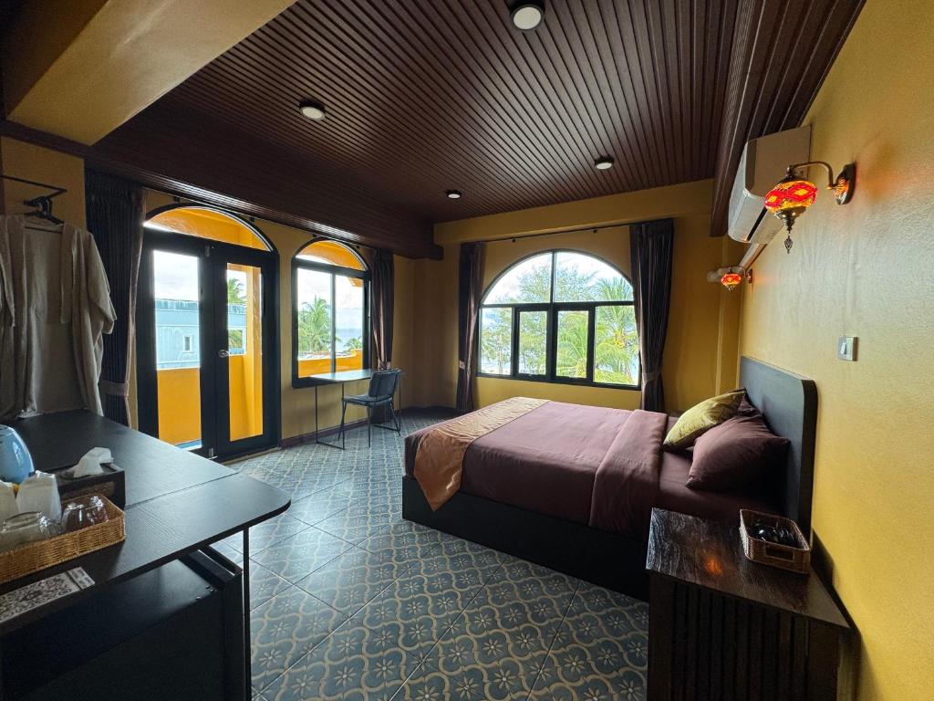 a bedroom with a bed and a desk and windows at Phoenix Room in Ban Tha Samet (1)