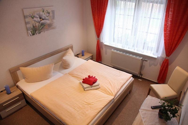 a bedroom with a bed with a red flower on it at Pension & Gasthof Storchennest in Groß Quassow