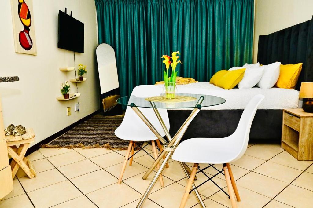 a room with a table and two chairs and a bed at Cozy Comfortable Apartment with pool in Pretoria
