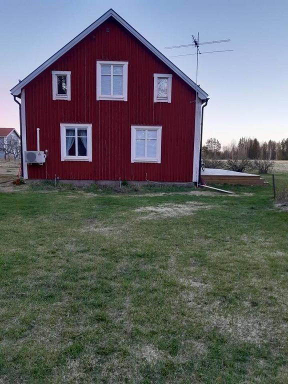 a red barn with white windows in a field at Workers Stay - Furnished Housing Umeå Sweden in Klabböle