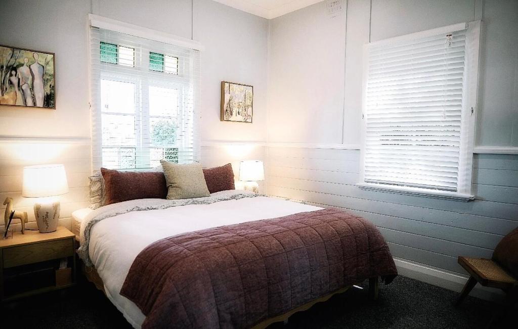 a bedroom with a bed and two windows at Maison Macquarie in Dubbo