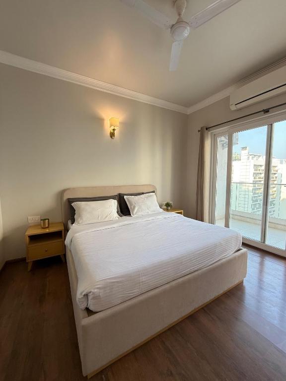 a white bed in a room with a large window at Central Park, The Rooms 1 & 2 BHK Poolview Suites in Gurgaon