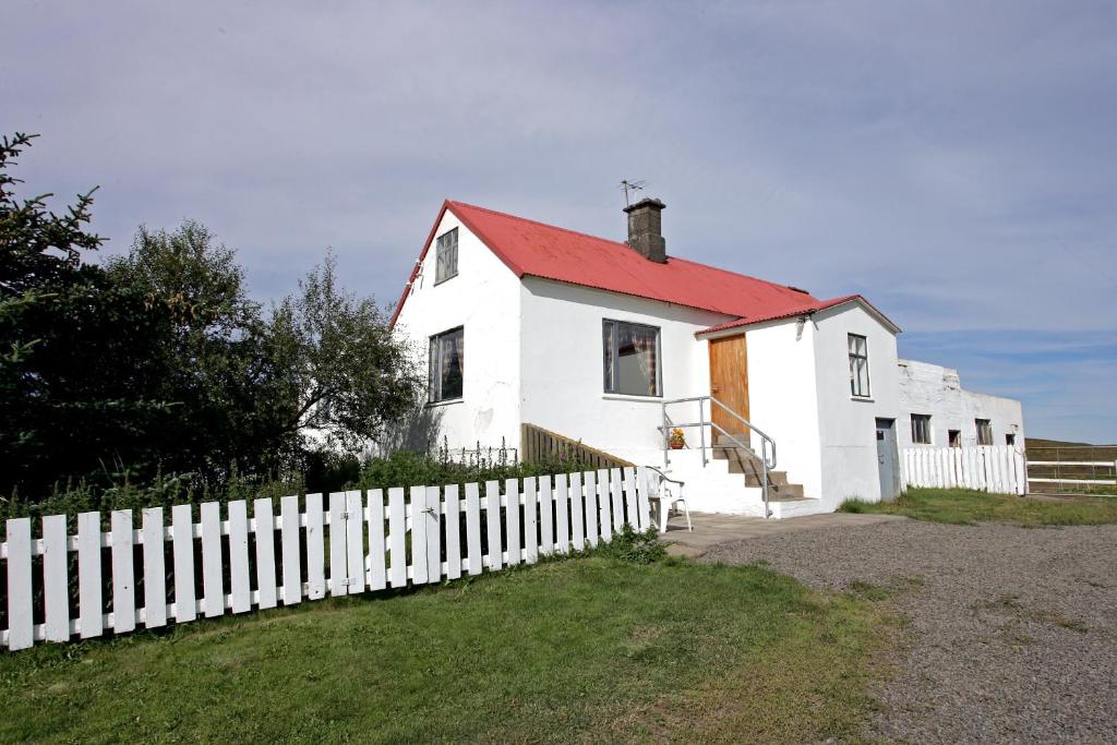 een wit huis met een rood dak en een wit hek bij apartment Neðra-Vatnshorn in Hvammstangi