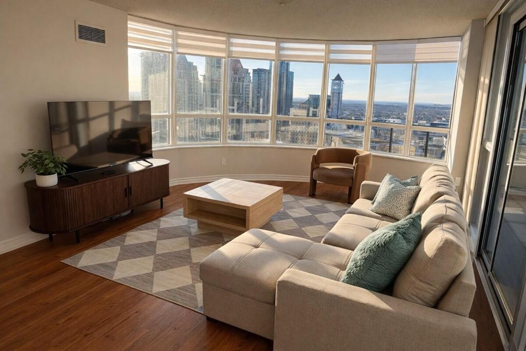 a living room with a couch and a flat screen tv at Skyline Retreat Floor-to-Ceiling Views in Mississauga