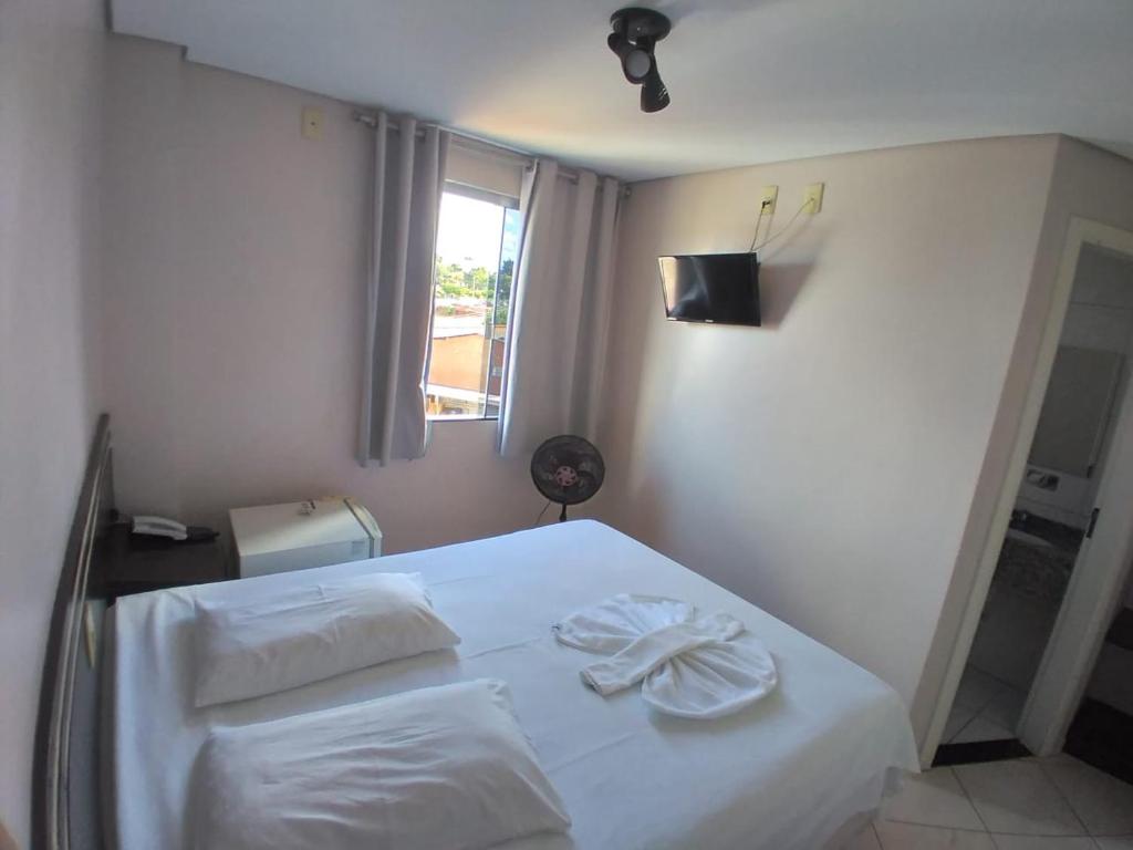 a bedroom with a bed with white sheets and a window at Florença Hotel in Quedas do Iguacu