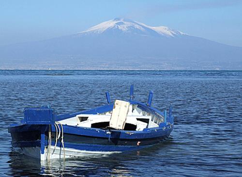 una barca blu in acqua con una montagna sullo sfondo di Villa California ad Agnone Bagni