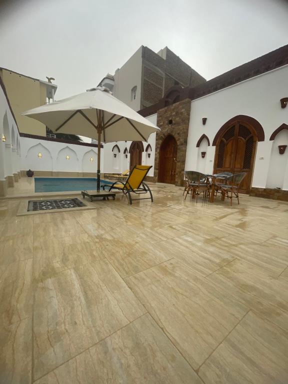 a patio with chairs and an umbrella and a pool at Oriental house in Luxor