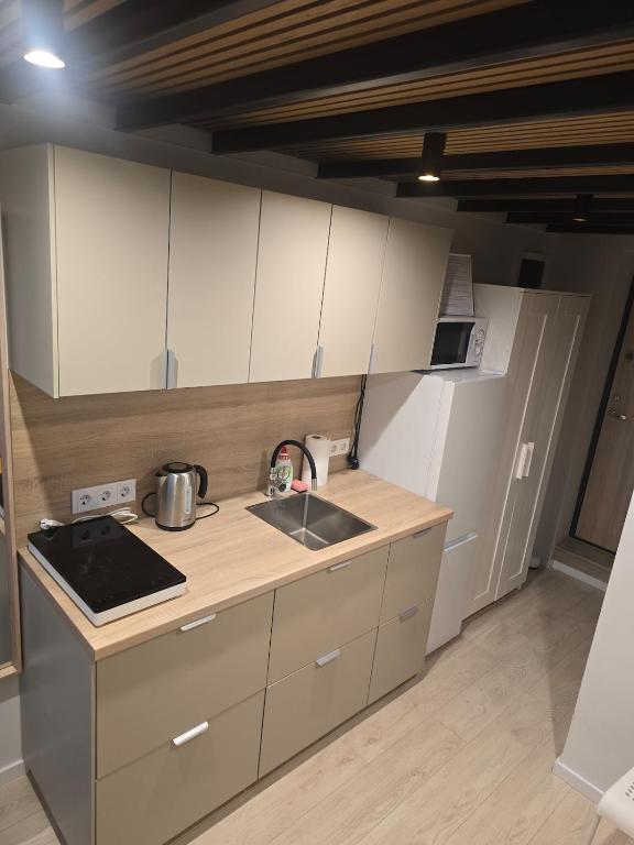 a kitchen with white cabinets and a sink and a stove at A&A Apartment Vilnius 2 in Vilnius