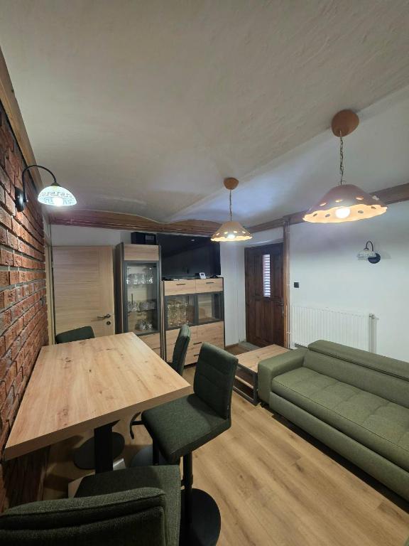 a living room with a table and a green couch at Tijekova koča in Hočko Pohorje