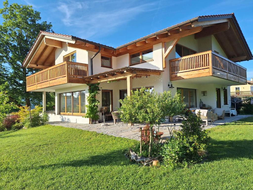 a house with a balcony and a yard at Wolke 8 in Bernau am Chiemsee