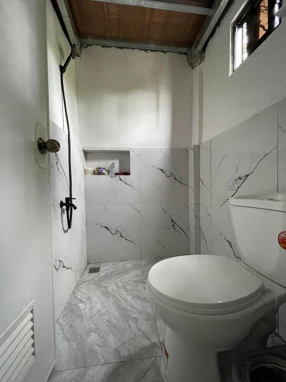 a white bathroom with a toilet and marble walls at Lavish style at Laguna by Nelson in Biñan