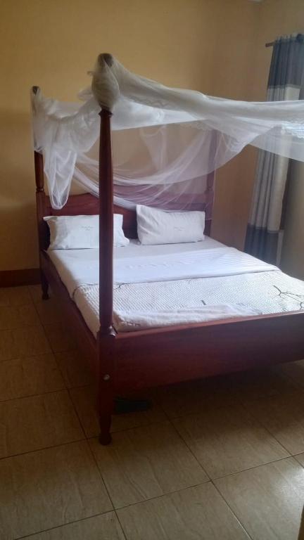 a wooden bed with a canopy in a room at Palace Royal Hotel in Kagadi