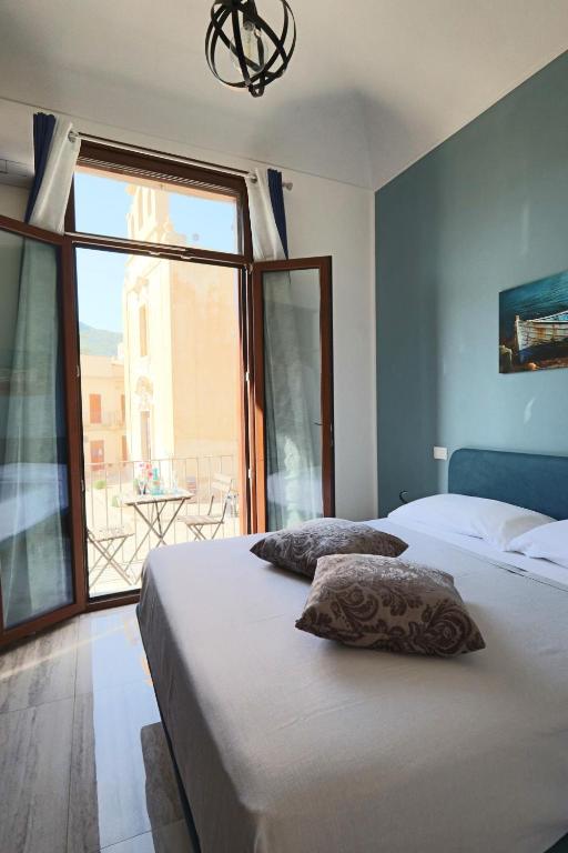 a bedroom with two beds and a large window at Agorà di Favignana - Affittacamere Piazza Madrice in Favignana