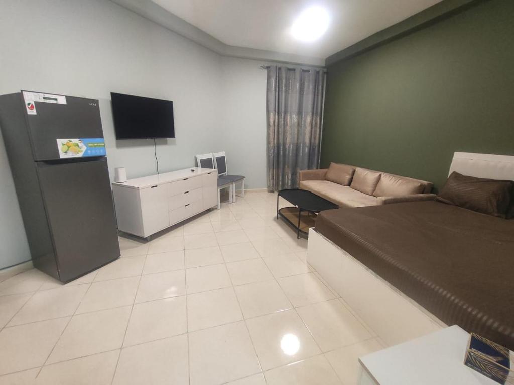 a large living room with a couch and a tv at Cozy Studio In Orient Towers Ajman in Ajman 