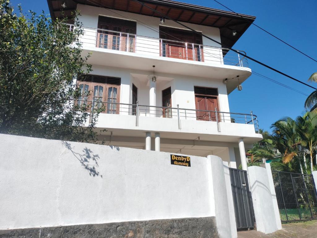 a white house with a sign on a wall at DenbyD in Tennekumbura