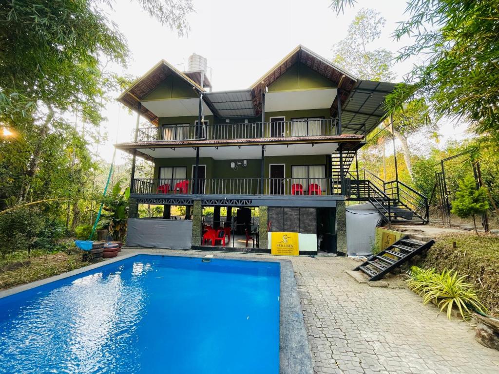 a house with a swimming pool in front of it at Stillora Hotel And Resorts in Sultan Bathery