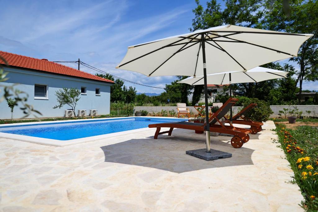 an umbrella and a chair next to a pool at Pomalo in Vrsi
