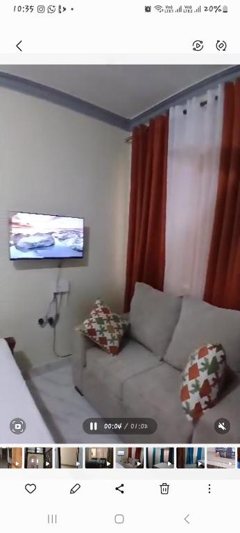 a living room with a couch and a flat screen tv at Dee Holiday Homes Studio-Bamburi Total in Mombasa
