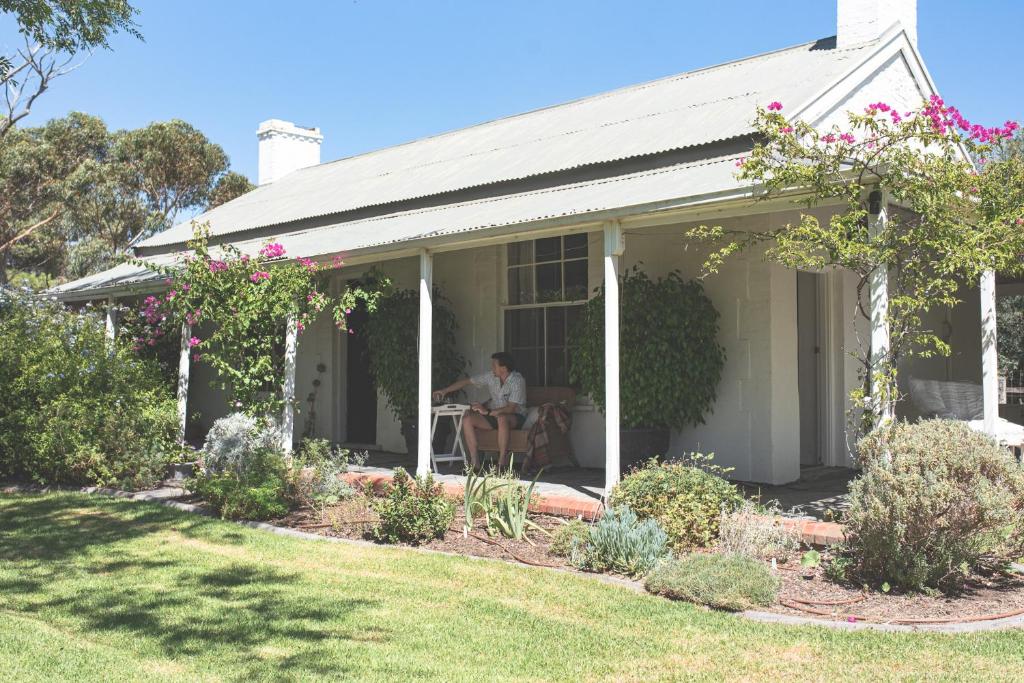 a woman sitting on the porch of a house at Way's Cottage in McLaren Vale