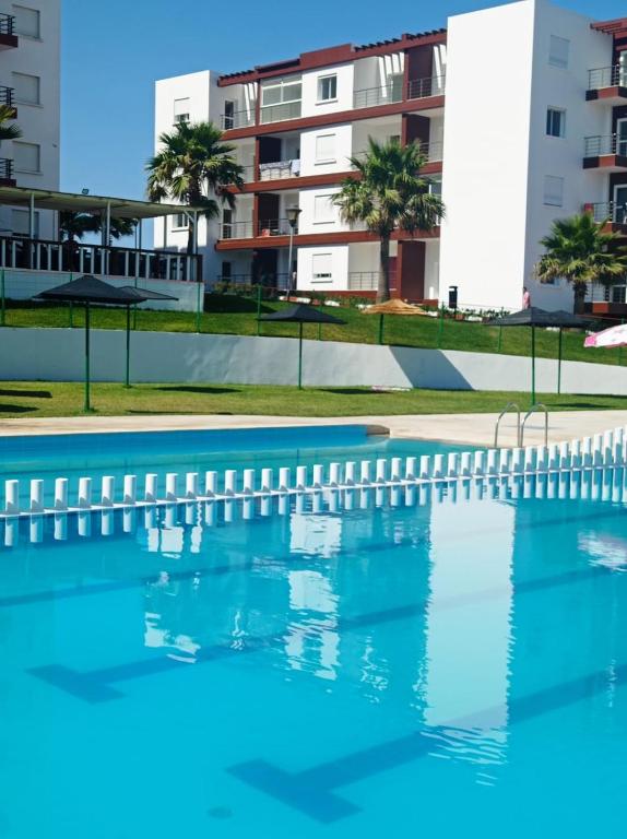 an empty swimming pool in front of a building at Atlantique Assilah Vue Mer, Piscines, Clim & Wi-Fi in Asilah