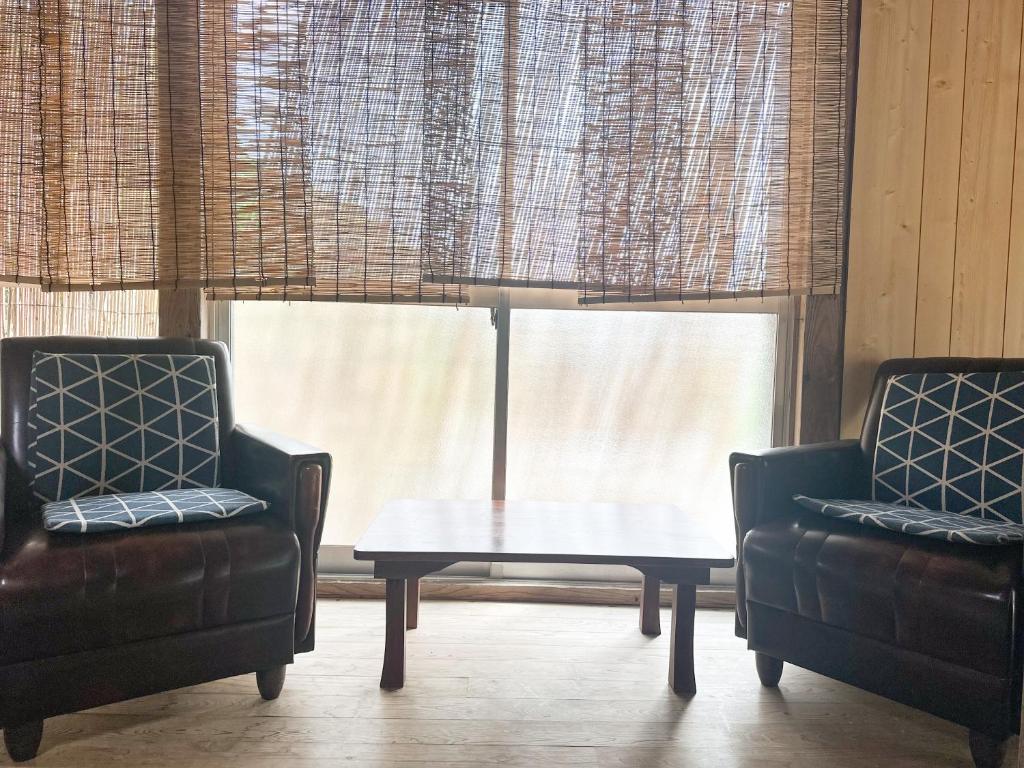 a living room with two chairs and a coffee table at 民泊Toshi29 in Wadomari