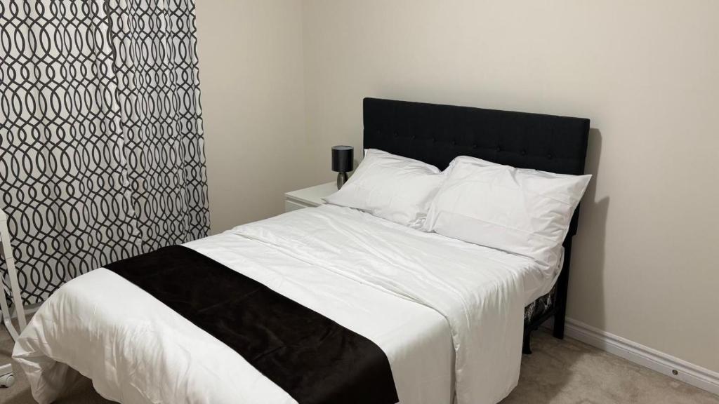 a bed with a black headboard and white sheets and pillows at Halton Hills Haven in Milton