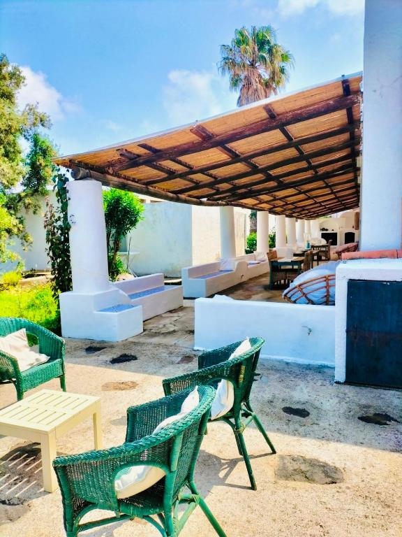 a patio with chairs and tables and a wooden umbrella at Dépendance Liscio in Filicudi