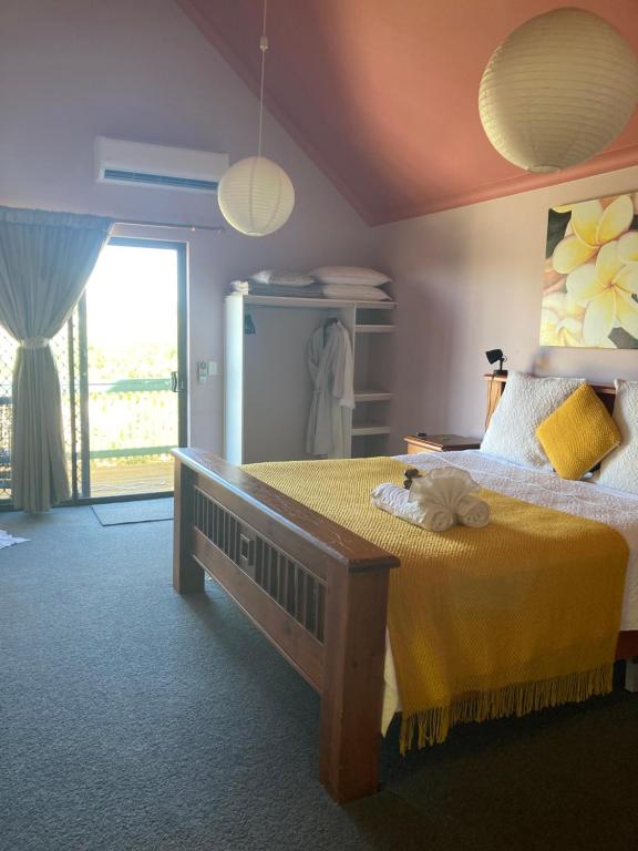 a bedroom with a large bed with a yellow blanket at Questro Lodge in Kalbarri