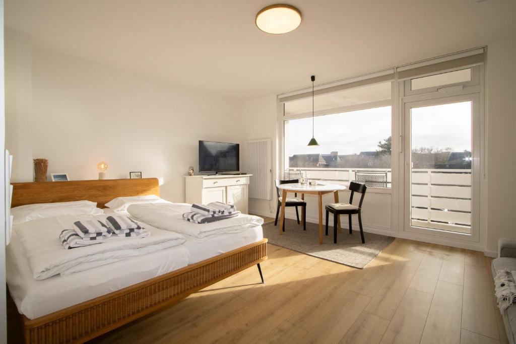 a bedroom with a bed and a table with chairs at Sylt for Friends in Hörnum