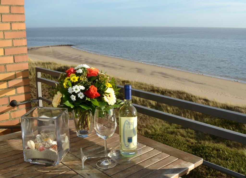 a table with a bottle of wine and a bouquet of flowers at Wattenblick 51-35 in List