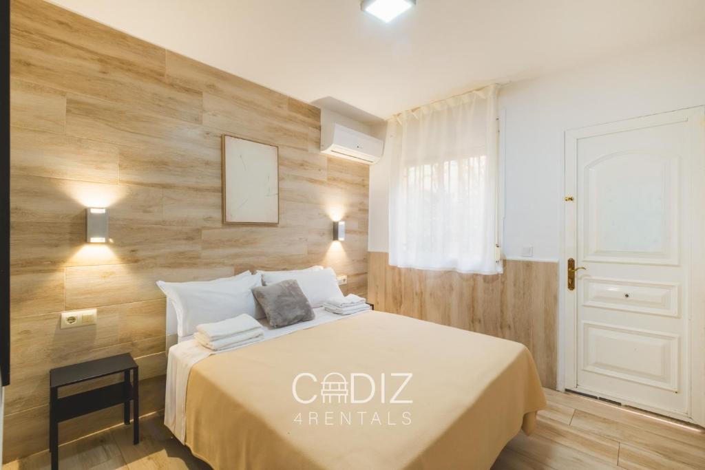 a bedroom with a bed with a wooden wall at Hospederia IMAR by Cadiz4Rentals in Cádiz