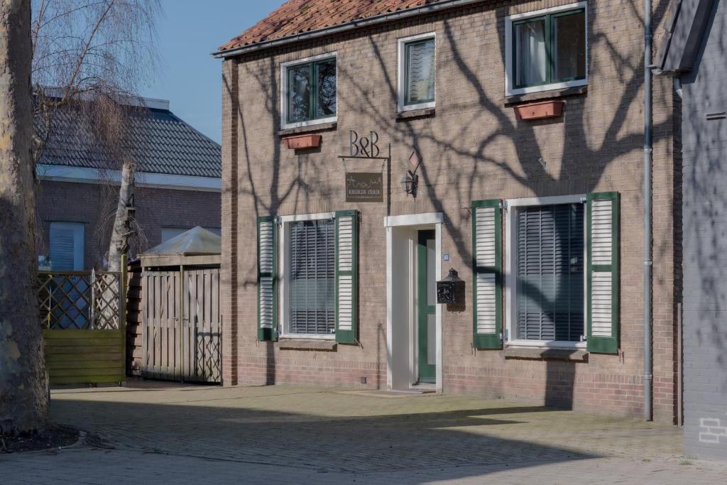 a brick building with green and white shutters on it at B&B Keukja Cuijk in Cuijk
