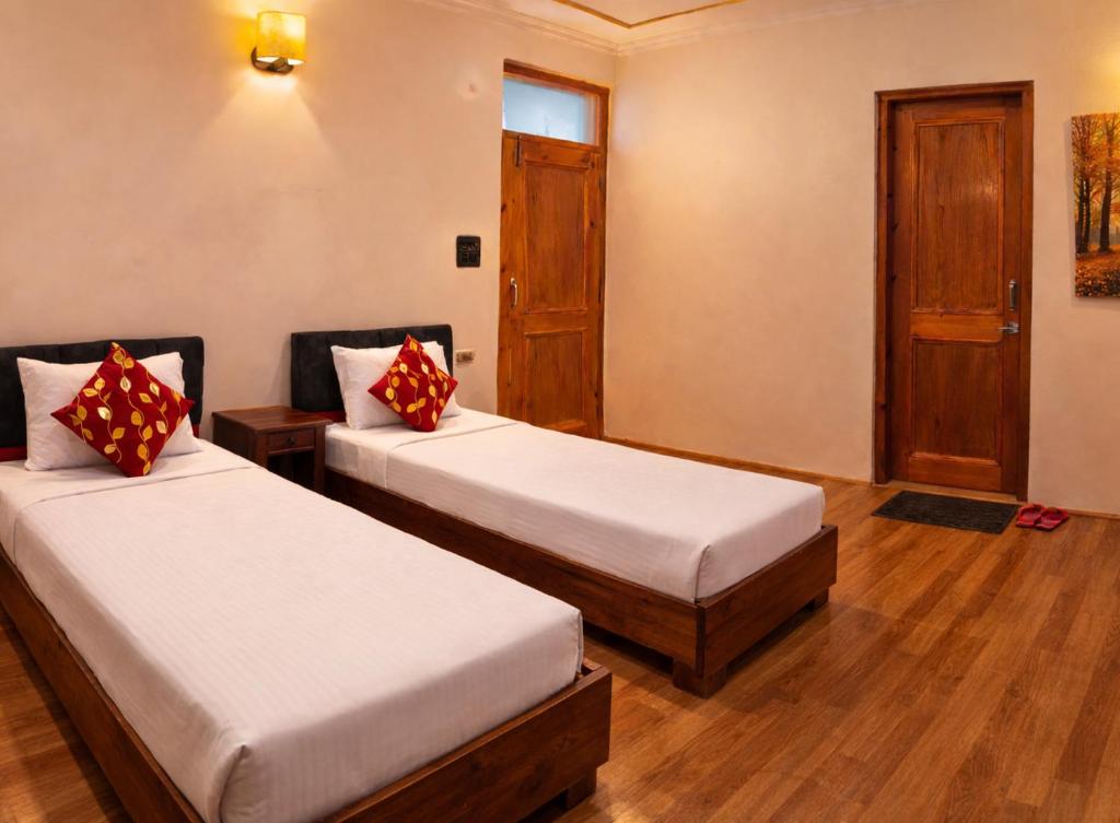 a hotel room with two beds and a door at RH Guest House Leh in Leh