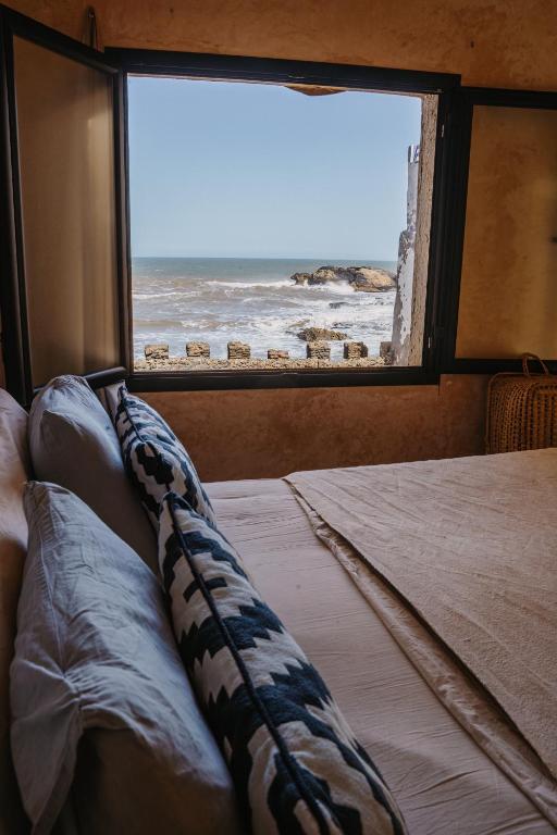 a bedroom with a window with a view of the ocean at Authentic Riad - Sea View & Rooftop Spa in Essaouira