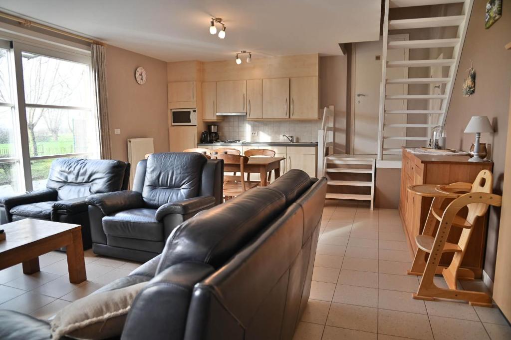 a living room with a couch and chairs and a kitchen at 't Ooievaarsnest in Veurne