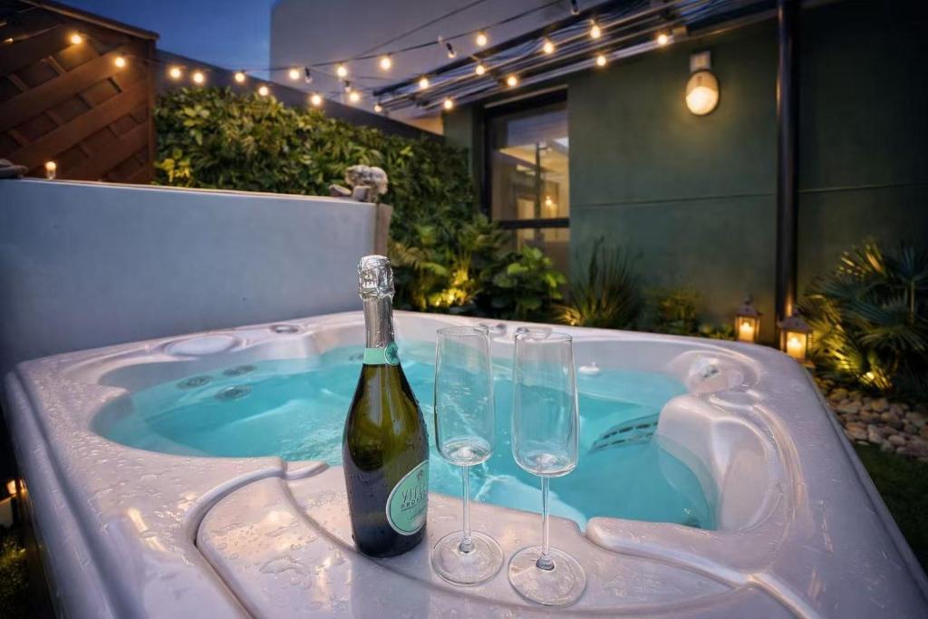 a hot tub with a bottle of wine and wine glasses at Skyline Luxury Penthouse Belfast City Centre in Belfast