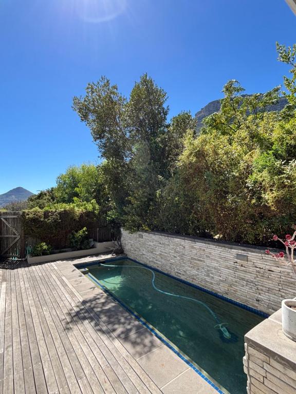 a swimming pool next to a brick wall and a wooden deck at 1 Fountain private pool in Hout Bay
