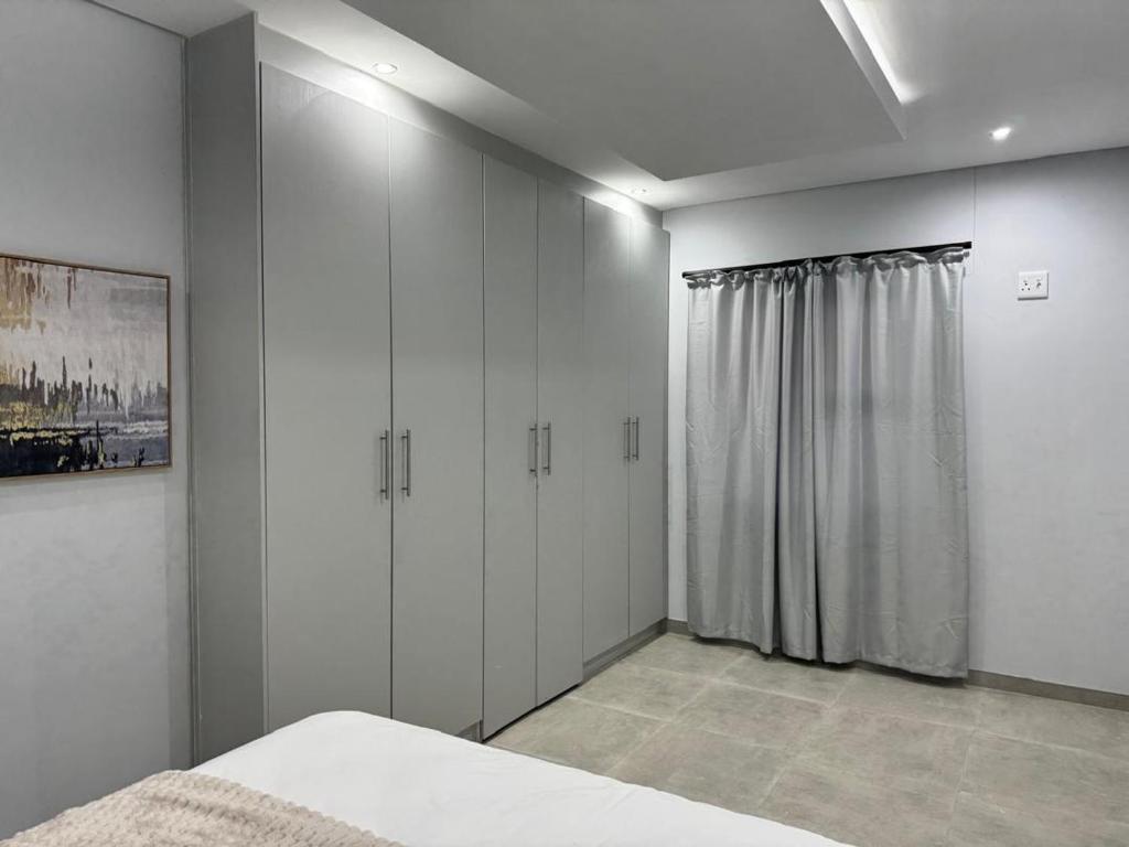 a bedroom with white cabinets and a bed in it at DECADE Self-catering in Swakopmund