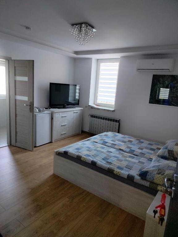 a bedroom with a bed and a flat screen tv at Noclegi i Restauracja Gracja in Bełchatów