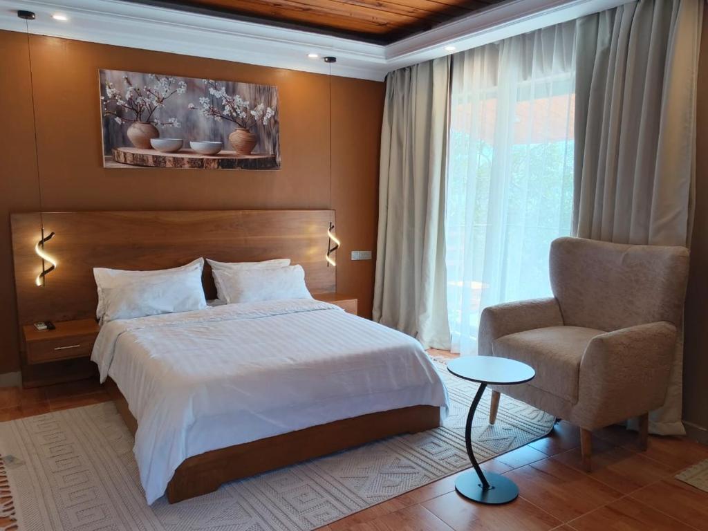 a bedroom with a bed and a chair and a window at Capri Hills in Mwanza