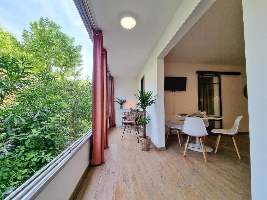 a balcony with a large window and a table and chairs at Écrin de Verdure - Design & Confort T2 38m2, WIFI, Piscine & Plage à 200m in La Grande Motte