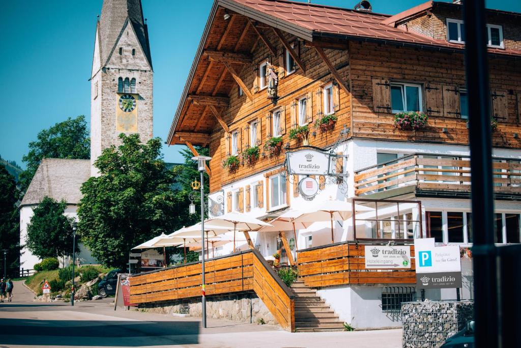 a wooden building with a clock tower in the background at Hotel Tradizio in Mittelberg