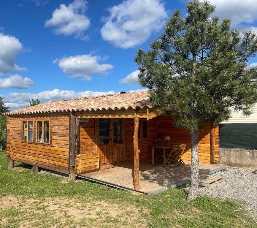 a log cabin with a table and a tree at Chalet LALi in Saint-Étienne-de-Fontbellon