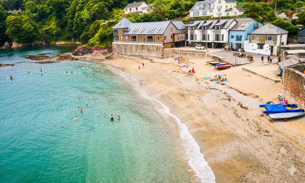 an aerial view of a beach with people in the water at Cosy Beach Cottage - Cawsand in Cawsand