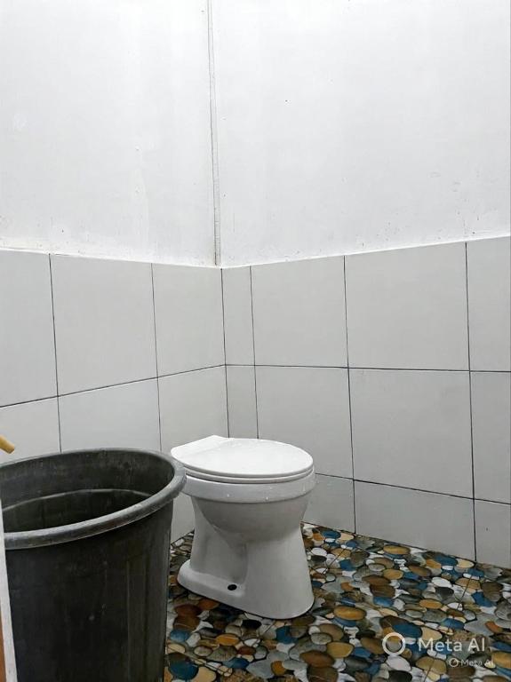 a bathroom with a toilet and a trash can at Tiga Dara Homestay 3 in Pangandaran