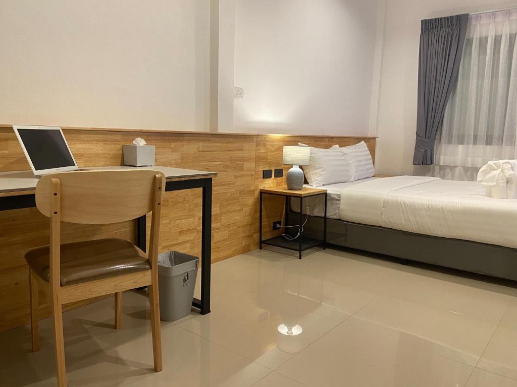 a bedroom with a bed and a desk with a laptop at B House Phuket in Chalong
