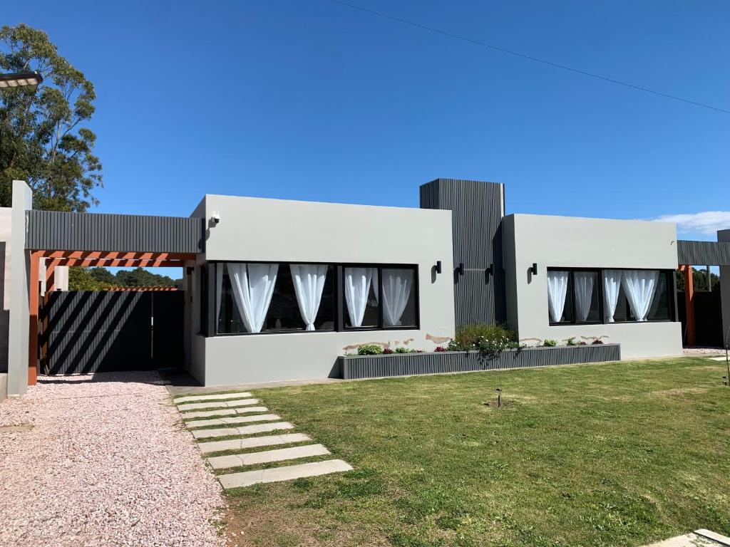 a large white house with a lawn in front of it at Casa 6 personas con piscina en Piriápolis Playa los Angeles in Piriápolis