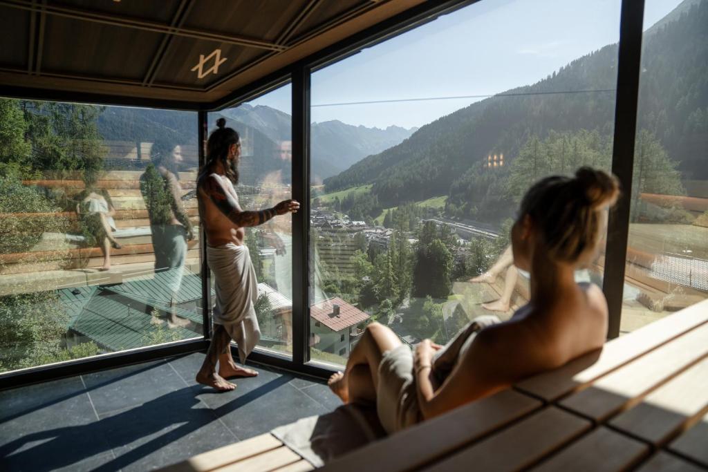 Eine Frau steht in einem Zimmer und schaut aus dem Fenster. in der Unterkunft ARPURIA - 4 Star Superior - Adults Only in Sankt Anton am Arlberg